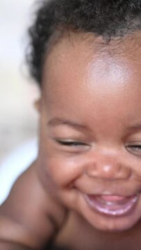 Vertical Video.afro american smiling baby lying down