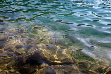 Transparent sea surface with stones on a bottom. Shallow water for background