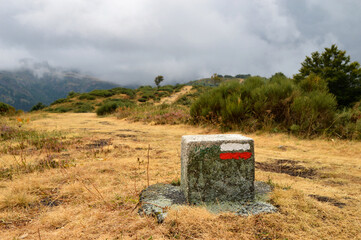A hiking trail with hiking trail signs or trail markers in the middle of a beautiful mountain landscape.