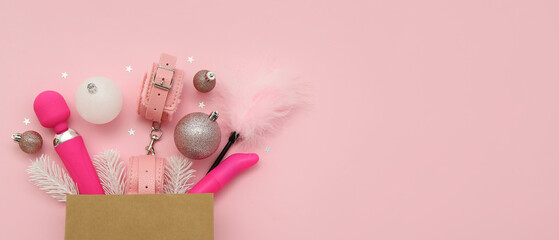 Box with different sex toys and Christmas decor on pink background with space for text
