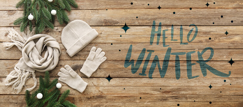 Banner with warm hat, gloves, scarf and text HELLO WINTER on wooden background