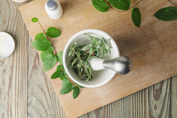 Mortar with herbs on light wooden table