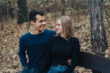 Young cheerful couple sitting on a bench in a park