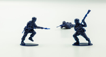 Close-up battle between two military toy soldiers against the white surface. Fighting soldier figure, plastic toys. two toy soldiers fighting against each other on a white background.