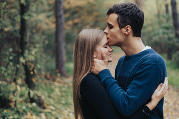 Boyfriend kisses girlfriend on the forehead in a forest