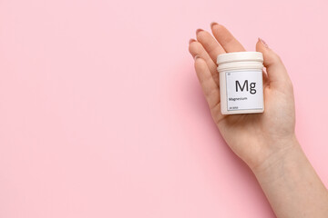 Female hand with jar of magnesium pills on pink background, closeup - obrazy, fototapety, plakaty