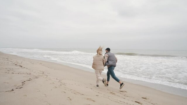Family couple walking hand in hand on the autumn beach along the ocean
