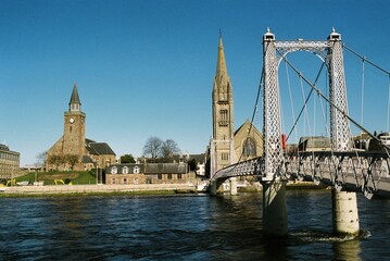 Fototapeta na wymiar Greig Street Suspension Bridge and Old High Church, Inverness.
