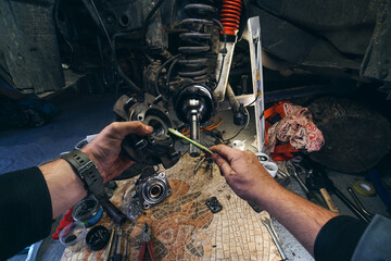 Car service from the first person mechanic. Male hands. Repair of the front wheel hub, replacement of bearings and oil seals, maintenance of a four-wheel drive SUV. Springs and shock absorber. © Sergey