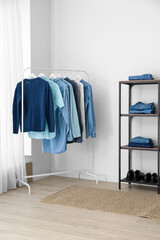 Shelving unit and rack with male clothes near light wall