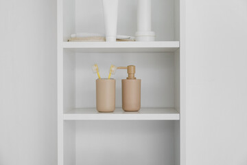 Bath accessories on shelf unit near white wall, closeup