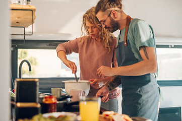 Young couple making breakfast together in the kitchen at home