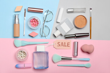Cosmetics, accessories and sale tag on color background