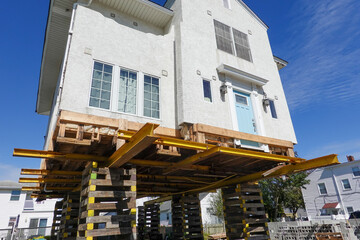 House on supports as it is being raised to protect it from raising flood waters due to global warming