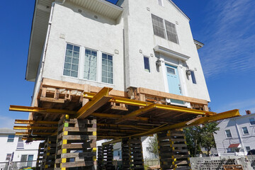 House on supports as it is being raised to protect it from raising flood waters due to global...
