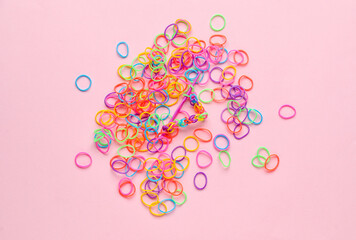 Colorful rubber bands and hook on pink background