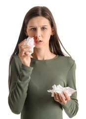 Young pregnant woman with nosebleed and tissues on white background