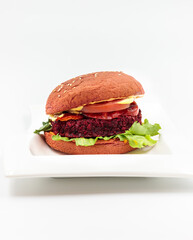 Vegan burger with beetroot cutlet, vegetables and grain bun. Isolate on a white background.