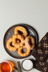 New Year's holiday content. A plate with donuts on a light background, with Christmas tree branches, knitted mittens and a cup with a drink