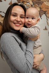 young pretty mother holds her little son in her arms, smiles, hugs. Young family, education of mother and son, emotions, hugs