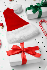 Christmas gifts and Santa hat on light background, closeup