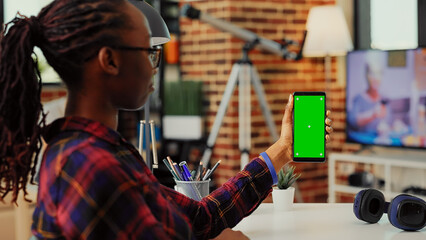 Modern person looking at greenscreen display on mobile phone, analyzing mockup template with blank chroma key and copy space. Vertically holding isolated background on smartphone.