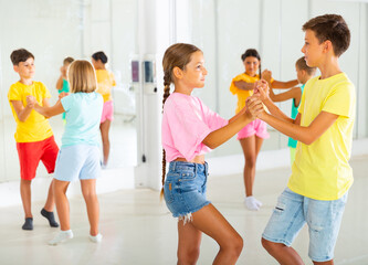 Active glad young children enjoying of partner dance in class