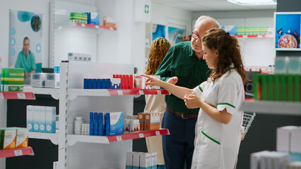 Pharmacist giving medical assistance to clients trying to buy medicine and packages with pills,...