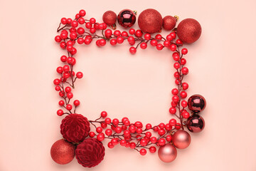 Frame made of Christmas balls and branches with red berries on color background