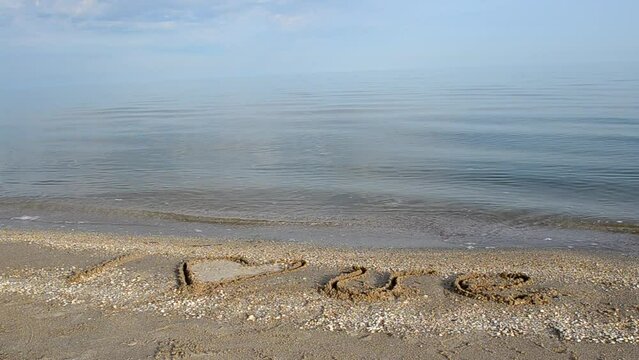 Inscription on sand. I love. Beach and sea.