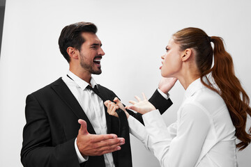 Man and woman pulling on tie anger business looking at each other screaming with hands up in white isolated background. The concept of business in a couple harassment startup copy space