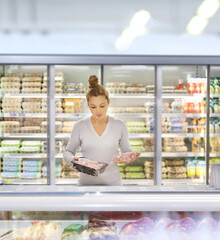 Woman choosing frozen food from a supermarket freezer