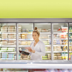 Woman choosing frozen food from a supermarket freezer