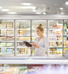 Woman choosing frozen food from a supermarket freezer