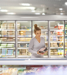 Woman choosing frozen food from a supermarket freezer