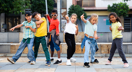 Positive girls and boys training hip hop on city street, outdoor dance class for kids
