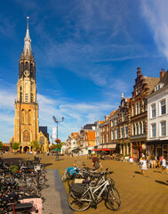 Fototapeta na wymiar Scenic view of historical central Cameretten square of Dutch city of Delft with peculiar typical townhouses, busy street cafes and Gothic belfry of medieval Protestant church Nieuwe Kerk on summer day