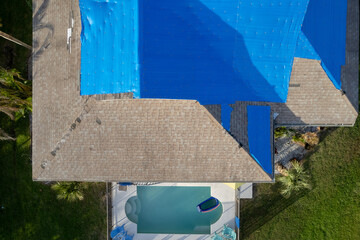 Hurricane Ian destroyed homes in Florida residential area blue tarp roof. Natural disaster and its consequences