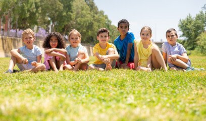 Group of happy kids on green grass in summer park