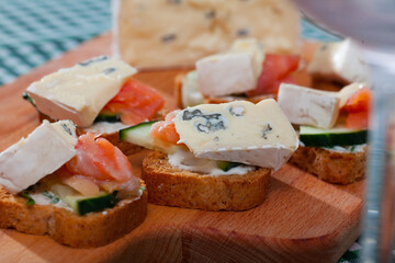 Appetizing canapes with slices of salmon and cambozola served on toasted baguette with cream sauce and cucumber