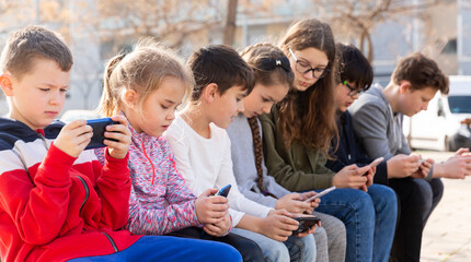Kids using phones outdoors, concept of children addiction to social network
