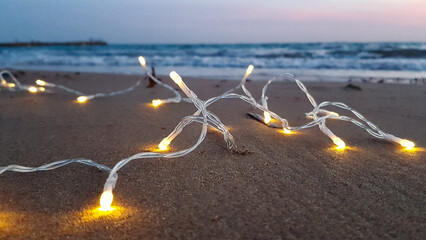 on a sandy beach, a Christmas garland glows