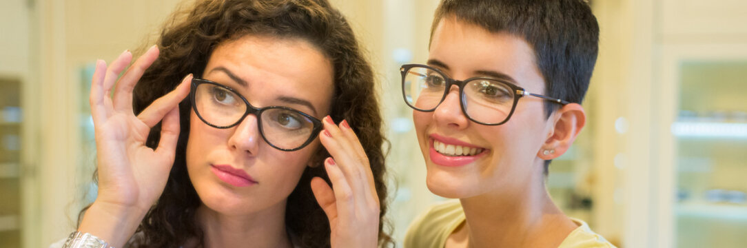 Young beautiful woman choosing eyeglasses in optical shop