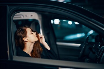 Fototapeta na wymiar a stylish, luxurious woman is sitting in a black car at night, straightening her long, styled hair