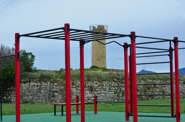 Fototapeta na wymiar Zona de calistenia con la torre del antiguo fuerte de la gales de fondo