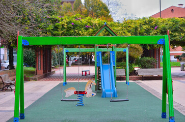 Parque infantil del municipio de Getxo con arboles y plantas verdes de flores moradas detrás