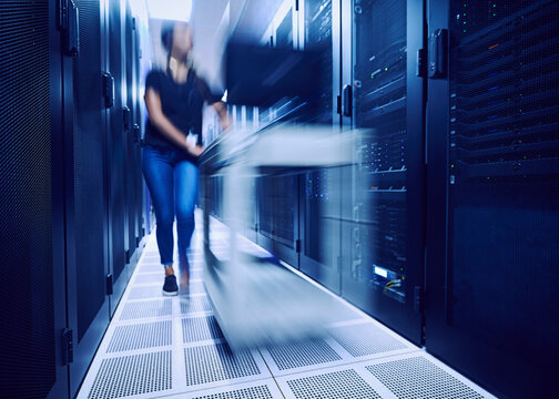 Female technician walking in server room, blurred in motion