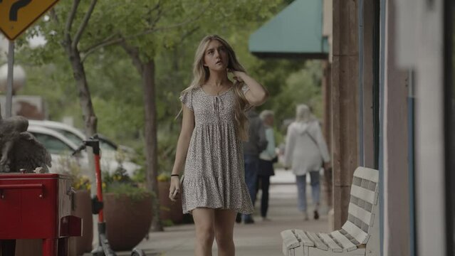Slow motion of teenage girl approaching on city sidewalk / St. George, Utah, United States