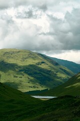 Vertical shot of green Scottish Highlands under the cloudy sky