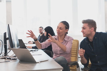 Collaborative process of multicultural skilled young business team during brainstorming meeting in office.Diverse group of young people dressed in formal wear cooperating on developing design project